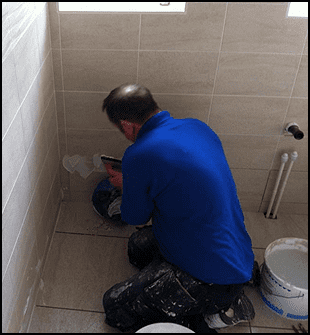 Contractor Using Tools to Install Tiles